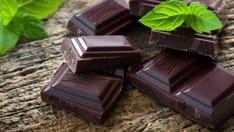 photo of Dark chocolate pieces. Dark chocolate patch with a mint leaf on the wooden background.
