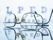 Myopic spectacles with a Snellen eye chart in the background 