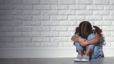 photo of Upset sad sad child girl in stress sits and cries at an empty dark wall
