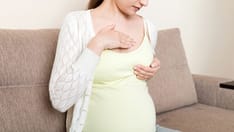 photo of Pregnant girl checks her breasts. Breast cancer prevention.