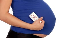 photo of Pregnant woman with pills isolated on a white background