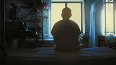 photo of Figure of sitting patient on a hospital bed on the background of bright lights