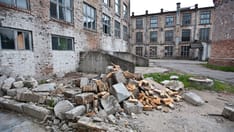 photo of War damaged buildings and debris from the buildings littering the ground nearby.