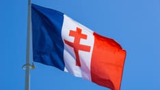 photo of Red Cross of Lorraine on a waving French flag against a blue sky. General de Gaulle symbol of WW2.