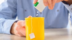 photo of Sweetener. Sweetener tablets and hand with cup of small piece of tea box