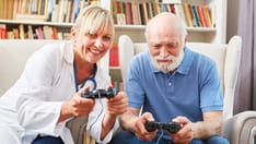 photo of Female doctor and senior man play video game in assisted living together