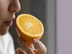 photo of a woman smelling an orange