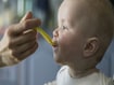 photo of mother spoon feeding her baby