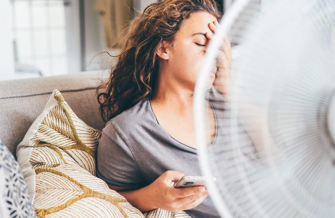 photo of woman using electric fan