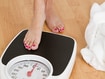 photo of Young woman stepping on a weighing scale