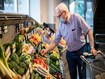 photo of Senior man with face mask buying vegetabl