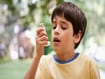 photo of Young boy using asthma inhaler