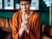 photo of Senior Asian woman rubbing her hands in discomfort.
