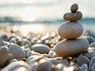 photo of Balanced stones on a pebble beach during sunset.