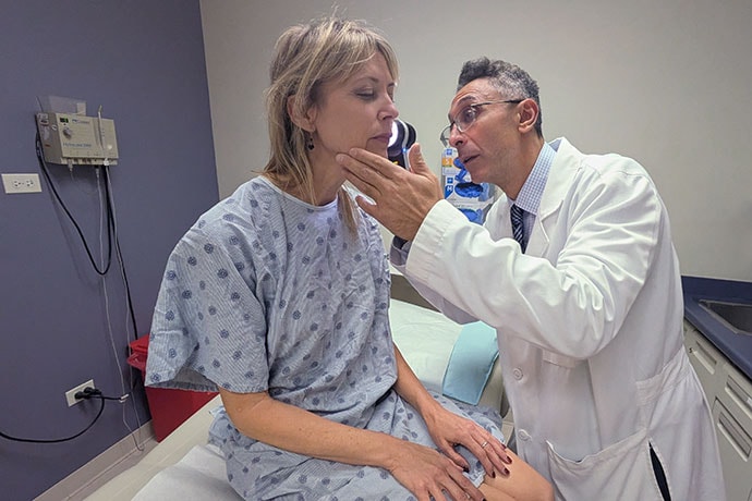 photo of Dr. Pedram Gerami examines the skin of patient and melanoma survivor Heidi Tarr.
