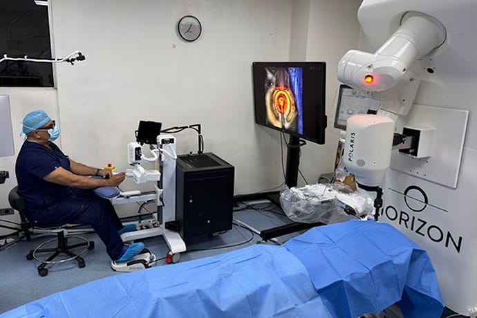 photo of Dr. Devgan at the console of the robot.