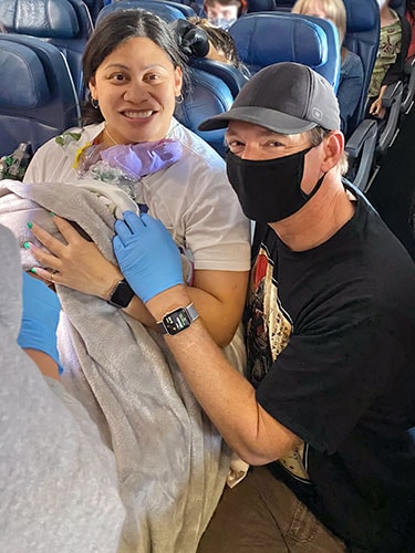 photo of Dr. Glenn with mother and baby on the airplane