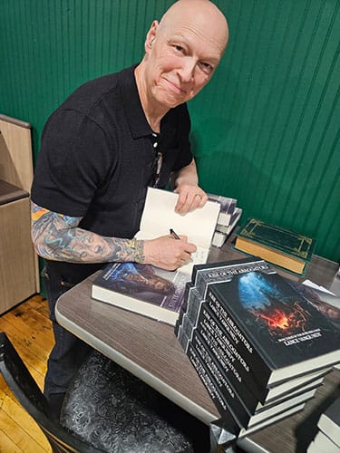 photo of Lance Van Gundy signs copies of a novel in his fantasy series.