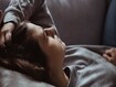 A person lying on the couch, fatigued.