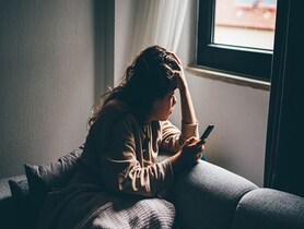 woman, depressed on smartphone, looking out of window